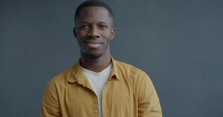 Slow motion portrait of cheerful African American man staring at camera through imaginary binoculars and smiling on grey color background - Powered by Adobe