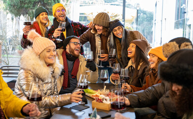 Fototapeta na wymiar Happy people group drinking red wine - Trendy young people at food street market - Winter friendship concept with friends enjoying time and having fun eating together - Focus mid man