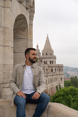 Close-up of a young male tourist posing looking sideways at the famous Fisherman's Bastion in Budapest.