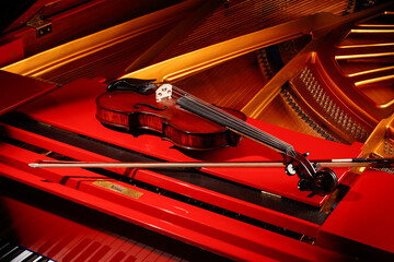 Classic Violin and bow on a red piano. Viola or fiddle on piano. Music concept. Selective focus