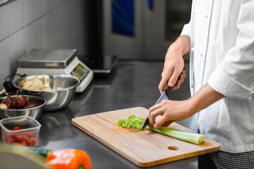 cooking food, profession and people concept - close up of male chef with knife chopping celery on...