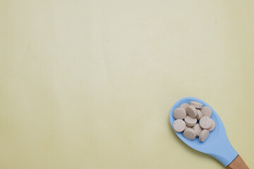Vitamins in a blue spoon on yellow background. with space for text