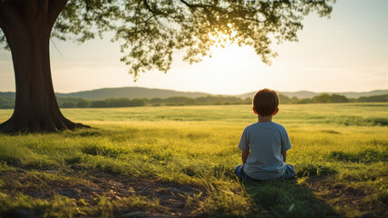 small boy sitting on the grass under a tree - Powered by Adobe