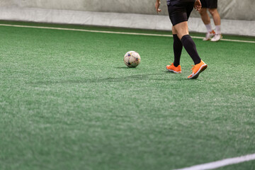 Mini soccer football players playing game in indoor stadium on artificial turf.