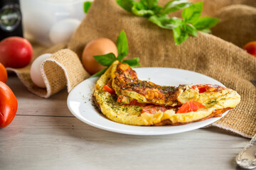 Stuffed omelette with tomatoes on a light wooden background.