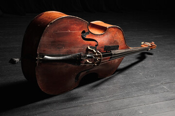 Classic acoustic vintage double bass on a black floor on the concert stage. Contrabass. Wooden...