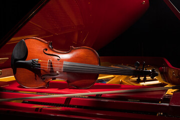 Violin and music. Classic Violin on a red piano. Viola or fiddle. Music concept. Selective focus
