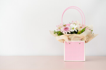 Bouquet of different flowers in pink box on white background.