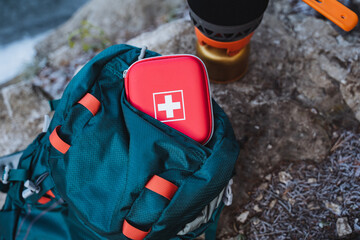 First aid kit is in the top pocket of the backpack, survival in the woods, camping in nature, safety on a hike. - obrazy, fototapety, plakaty