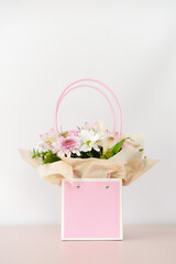 Bouquet of different flowers in pink box on white background.
