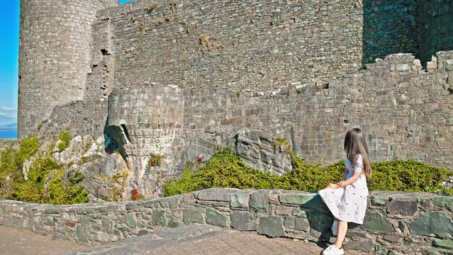 Beautiful woman visits medieval Caernarfon Castle in in Gwynedd, north-west Wales. Imposing World Heritage fortress by the river, offering a museum, exhibitions and family tickets.
