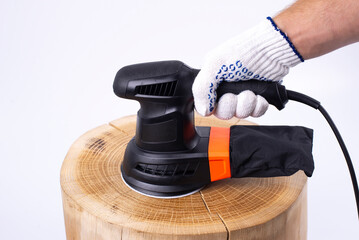 Eccentric grinding machine. Tree trunk. Oak board. Carpentry works. Hands of the master in gloves....