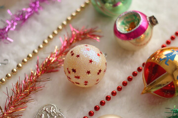 Colorful vintage Christmas ornaments and white faux fur blanket. Cute and kitschy Christmas decorations. Selective focus.