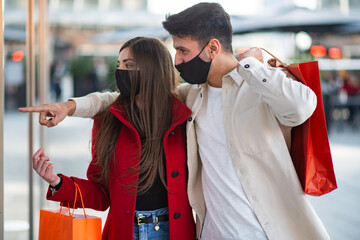 Covid and coronavirus shopping, couple walking in a city while carrying shopping bags