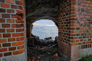 Old abandoned brick military fort with broken wall and view sea.