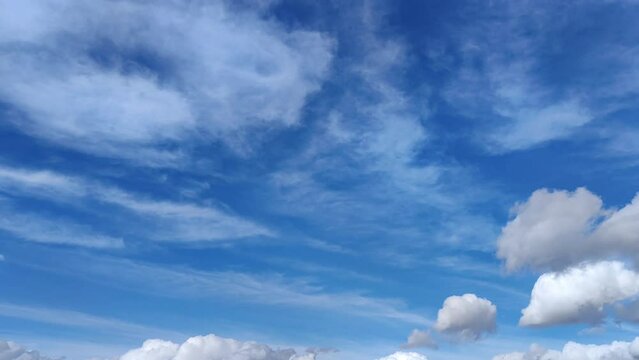 Cirrus clouds with some cumulus clouds circulate across the blue sky in the afternoon