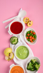Bowls with baby food on pink background. Healthy eating concept.