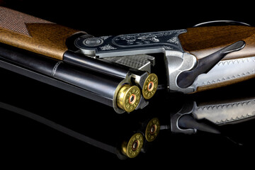 Over and Under Shotgun Loaded with Cartridges on a Reflective Black Surface - 674834341