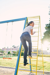 Young laughing woman climbs the stairs at the playground turning around. Back view