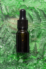 Skin care serum and set of essential oils on abstract background with fresh green leaves and...