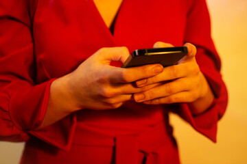 Using mobile  in female hand close up on a neon glowing background. Woman using cellphone.