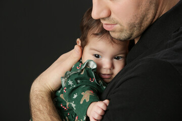 Studio portrait of father holding his little baby girl in green Christmas outfit, winter holiday,...