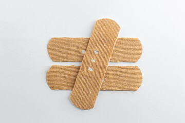 Band-Aids on a white background. Mathematical sign made with band-aids, not equal.