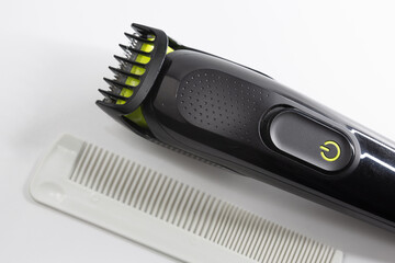 Electric shaver and plastic comb used for shaving hair, beard and moustache on a white background....