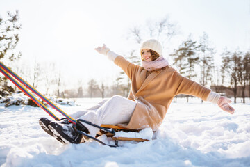 A young woman with a sled rides in a snowy park. Beautiful woman having fun outdoors on winter...