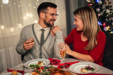 Couple drinking wine and laughing while sitting around a dining table during a dinner party