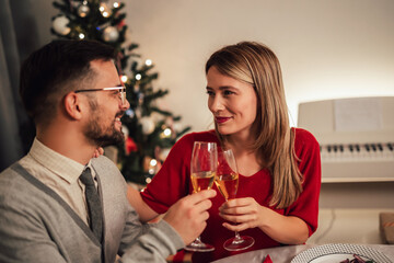 Couple drinking wine and laughing while sitting around a dining table during a dinner party