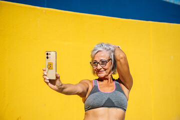 Sensual senior woman in sports clothes taking a selfie