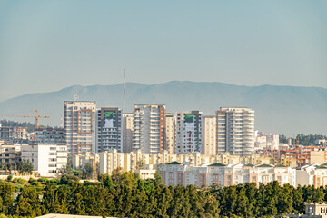 Residential buildings from a distance with two huge Algerian flags hanging from the facades. Trees...