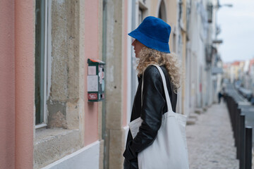 woman standing on a path of lisbon in portugal and looking in a window on a bright and pink street