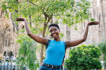 Afro tourist raising arms showing a famous Church