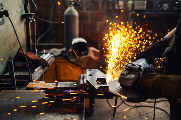 Focus on man's hands in safety gloves working with a grinding machine.