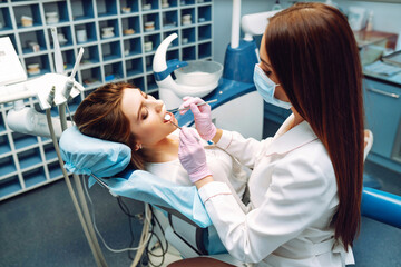 Young woman in the dentist's chair during a dental procedure. Dental health. Happy woman with a beautiful smile at a dentist appointment. Medicine, health concept