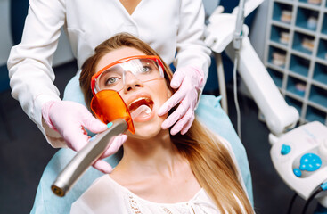 Young woman in the dentist's chair during a dental procedure. Dental health. Happy woman with a beautiful smile at a dentist appointment. Medicine, health concept
