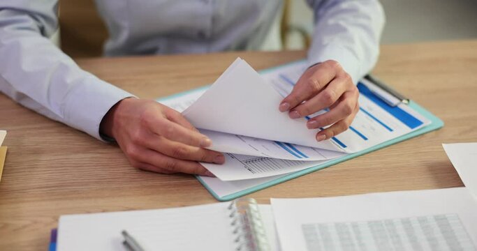 Employee sits at table in office and carefully analyzes work materials