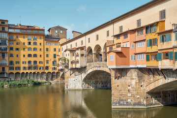 Fototapeta na wymiar Close-up of the old bridge seen from the right side, jewelers' shops in the foreground and the Arno river in Florence