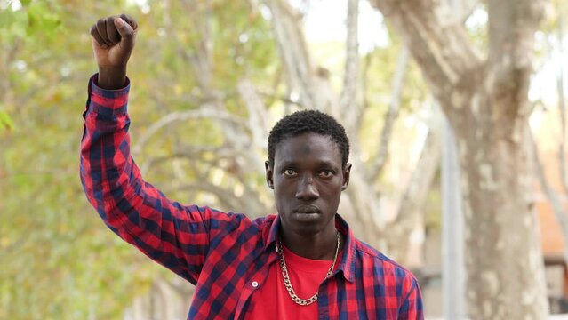 portrait of young black man with clenched fist as gesture of protest against racism