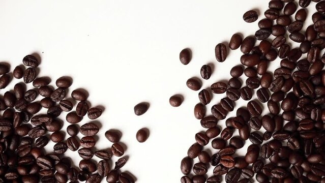 Video footage of coffee beans hitting each other in the center of an image on a white background.