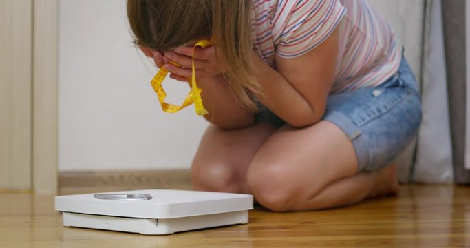 Scales and depressed, frustrated and sad woman crying while sitting on the floor