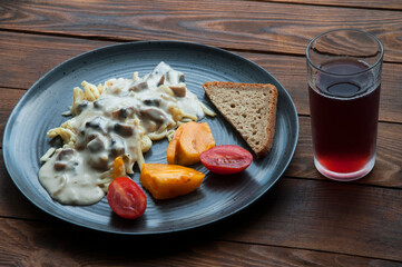 spaghetti with sauce, tomatoes and bread in a gray plate. light breakfast concept. cooked pasta with vegetables and mayonnaise	