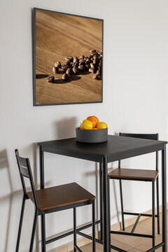 High bar table with chairs and fruits in bowl near white wall