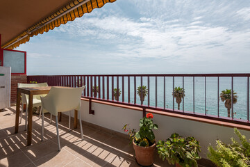 Cozy terrace with small table and houseplants on sea coast