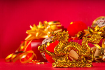 Chinese New Year 2024 greeting card. Bright red asian year of the dragon background with golden dragon figurine, Chinese lanterns, traditional jewelry, gifts, coins, cookies with wishes, copy space