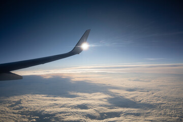 Obraz premium View of the wing of an airplane in mid-flight with clouds in the background
