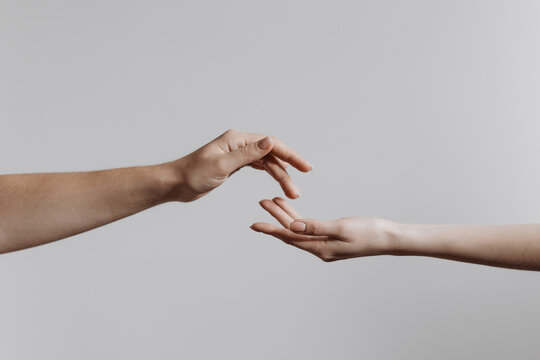 Hands touching each other isolated on grey background. Concept of human relation, community, togetherness, teamwork, love, symbolism, culture and history. 