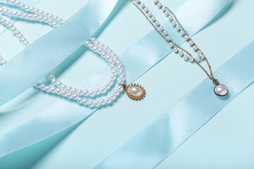 Ribbon with pearl necklaces on blue background, closeup